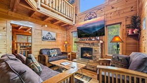 Interior acogedor de una cabaña con chimenea, muebles de madera y un mural decorativo con vistas panorámicas.