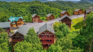 Un albergue con varias cabañas de madera, una carretera central y colinas boscosas circundantes.