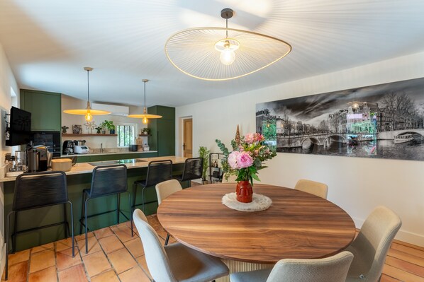 Una cocina moderna con comedor, que presenta una mesa redonda de madera, sillas y un jarrón decorativo.