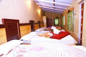 Een hotelkamer met een houten hoofdeinde, een bed met een bloemenprint beddeken en een raam met gordijnen.