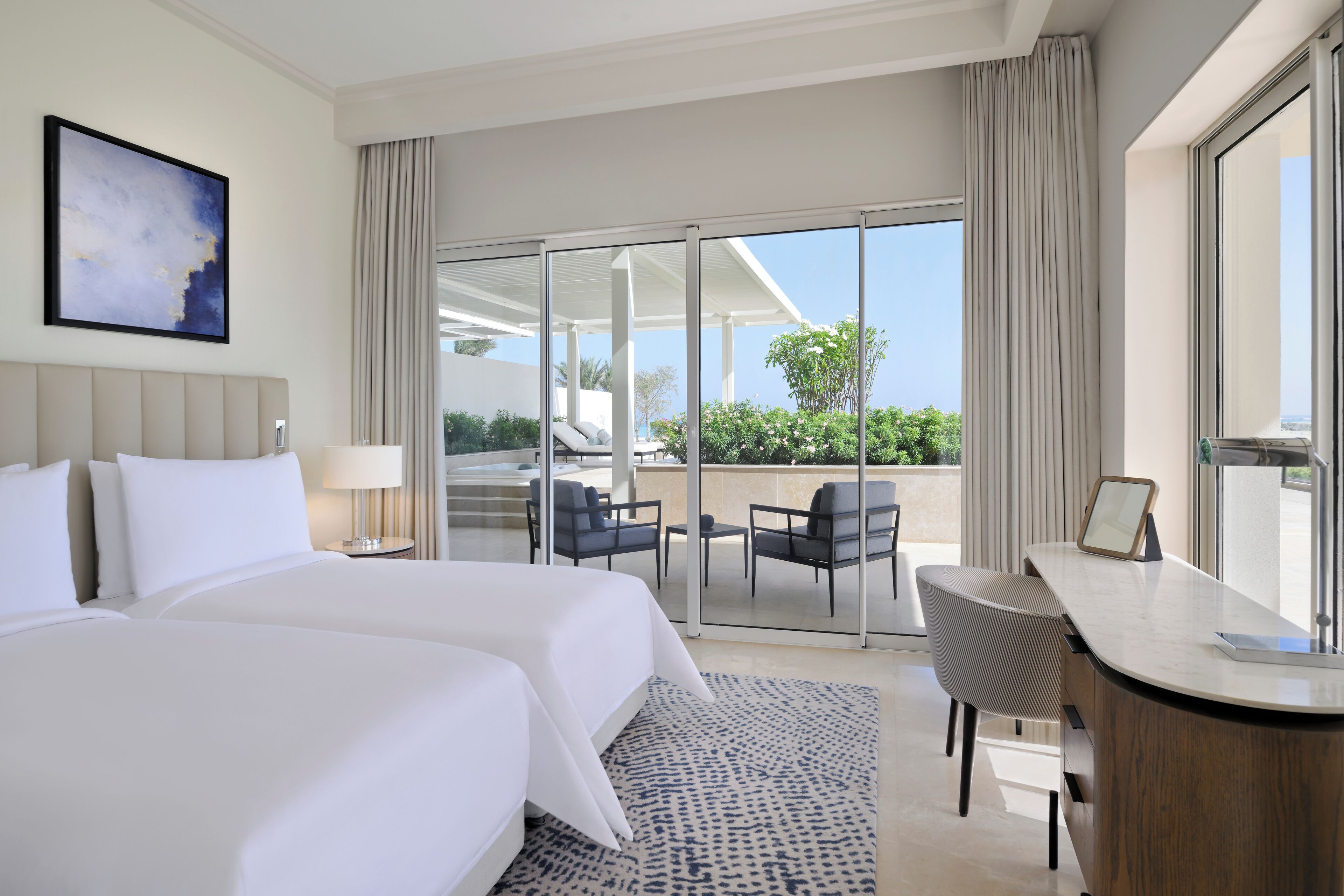 Une chambre d’hôtel avec un grand lit, un bureau et un balcon équipé de chaises.
