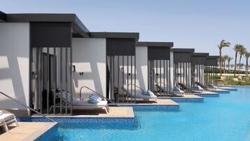 A poolside area with multiple lounge chairs and overwater bungalows.