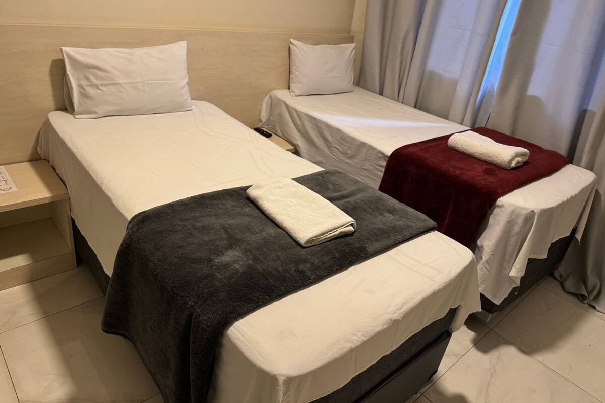 Hotellihuone, jossa on kaksi erillistä sänkyä, ja molemmissa on valkoinen tyyny ja peitto.