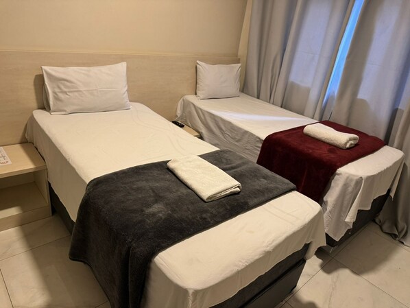 A hotel room with two single beds, each with a white pillow and a blanket. - Hotel Flex Tatuapé  (Sao Paulo)