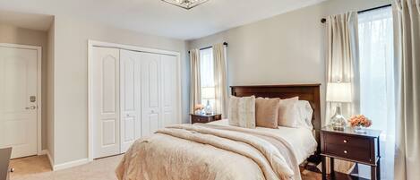 A bedroom with a large bed, a nightstand, a dresser, and a closet.
