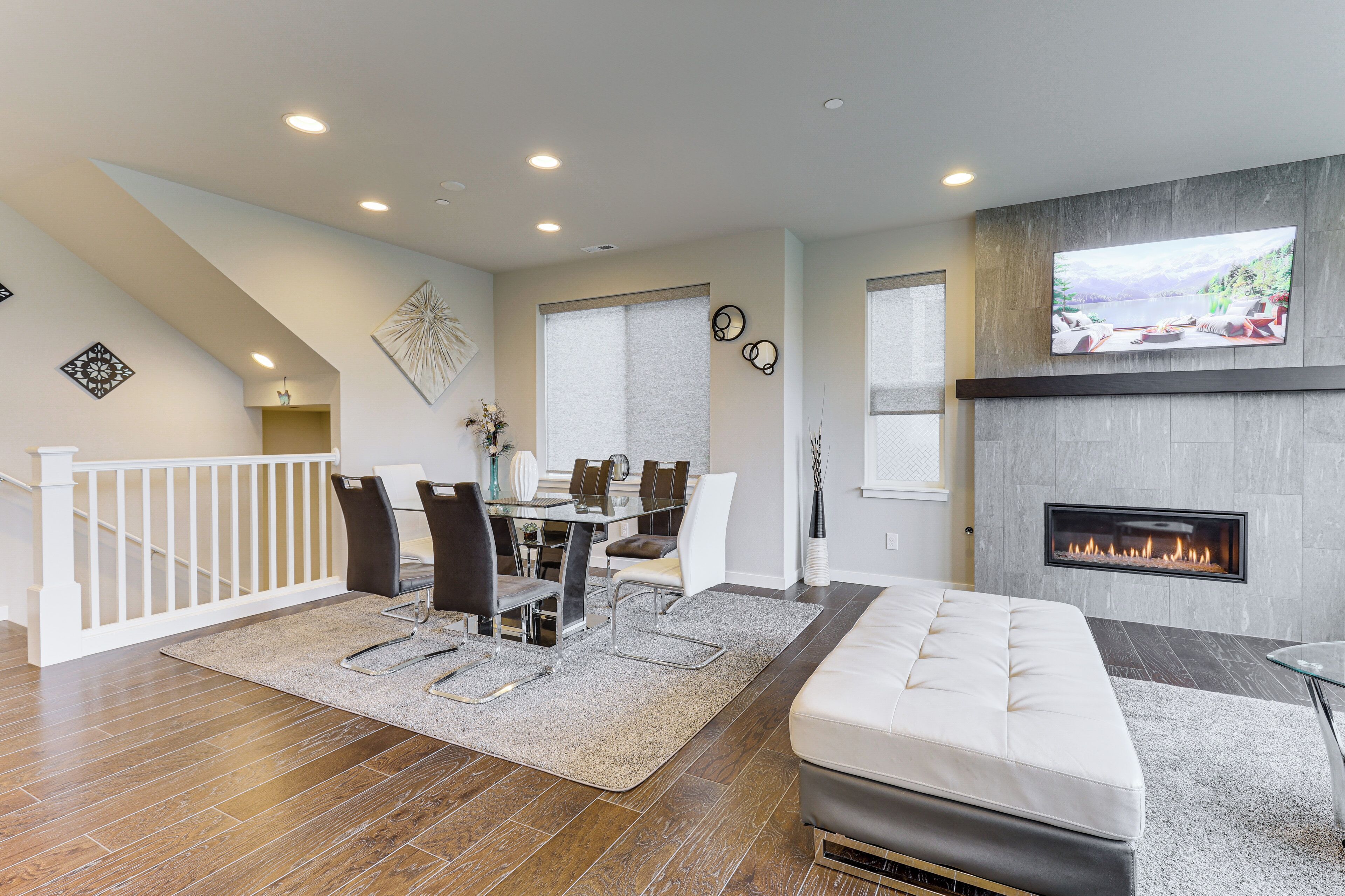 A modern living room with a fireplace, a dining area, and a staircase.