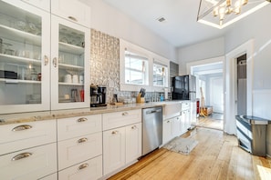 A modern kitchen with white cabinetry, a dishwasher, and a countertop with various kitchen items. - Walk to Midtown: Charming Reno Retreat (Reno)