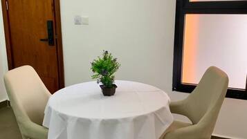 A round table with a white tablecloth, two beige chairs, and a small potted plant.