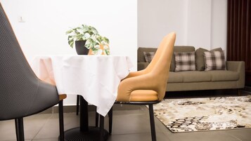 A modern living room with a sofa, a dining table with a white tablecloth, and a potted plant.