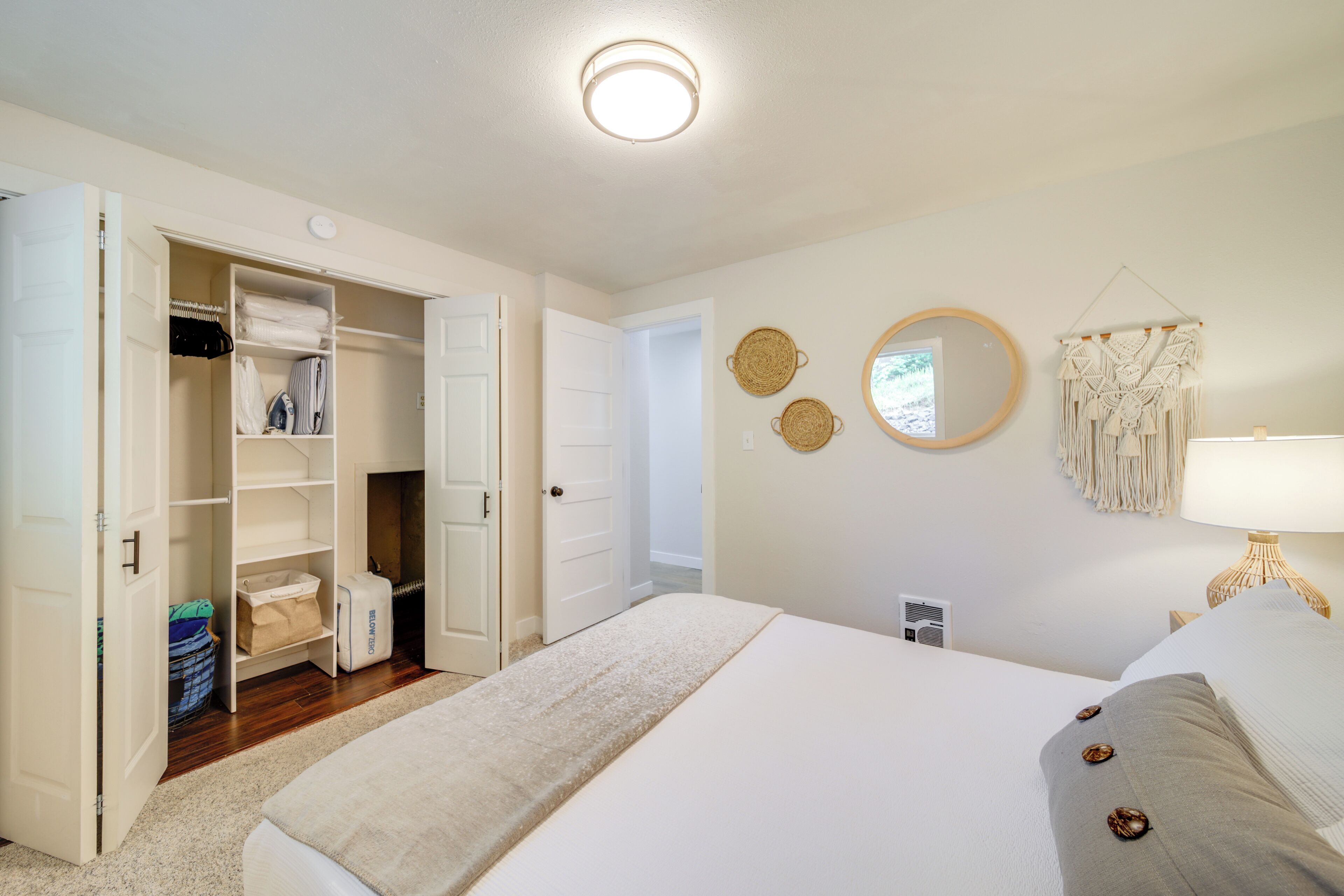 A bedroom with a large bed, a closet with open doors, and a wall-mounted macrame piece.