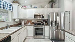 A modern kitchen with white cabinets, stainless steel appliances, and granite countertops. - Discover Your Perfect Summerhill Retreat with 2-Bed, 2-Bath, and Golf Cart! (The Villages)