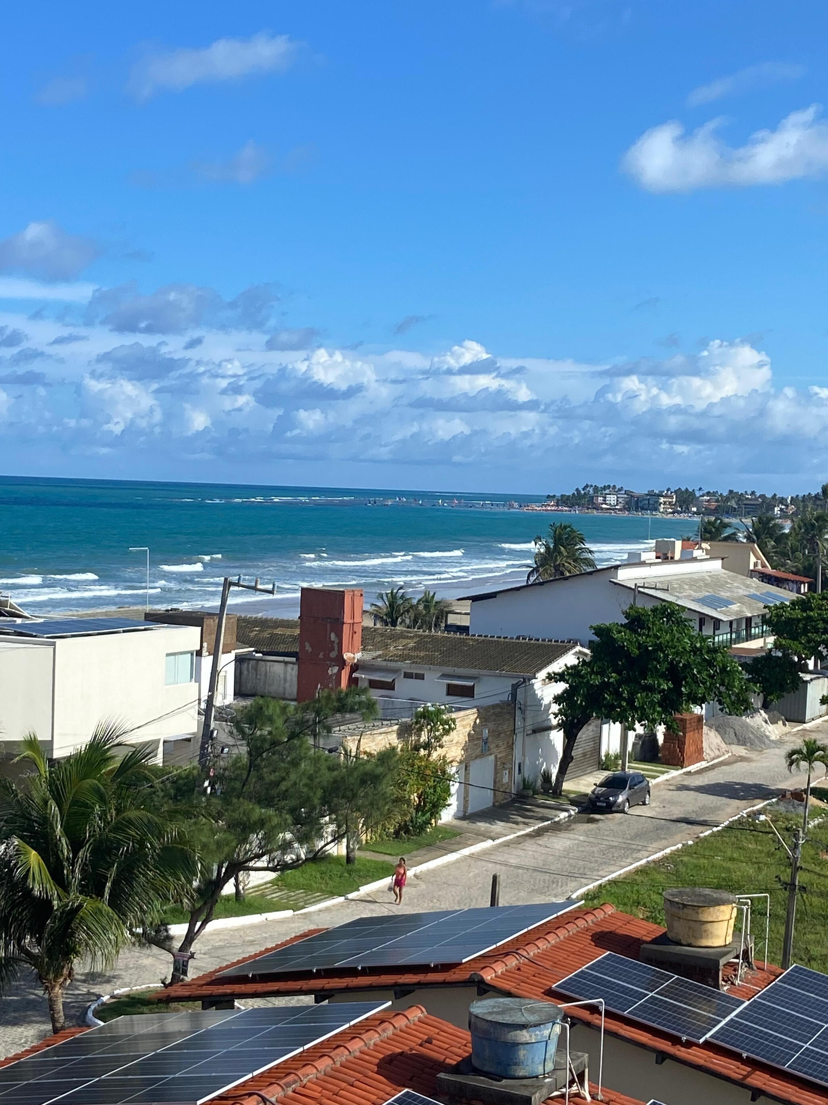 A coastal residential area with houses, solar panels, and a view of the ocean.