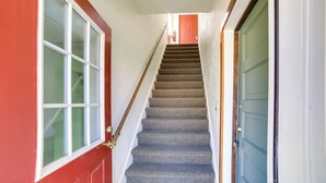 A staircase with a wooden handrail leading to a red door at the top. - 10 Mi to Lake Superior: Eben Junction Townhome! (Eben Junction)