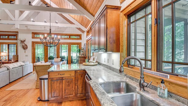 A spacious kitchen with wooden cabinets, granite countertops, and a large window.
