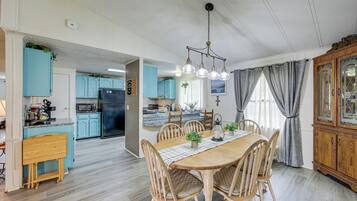 A spacious dining area with a wooden table and chairs, a kitchen with light blue cabinets, and a wooden cabinet with glass doors.