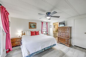 A bedroom with a bed, a dresser, a ceiling fan, and a television.