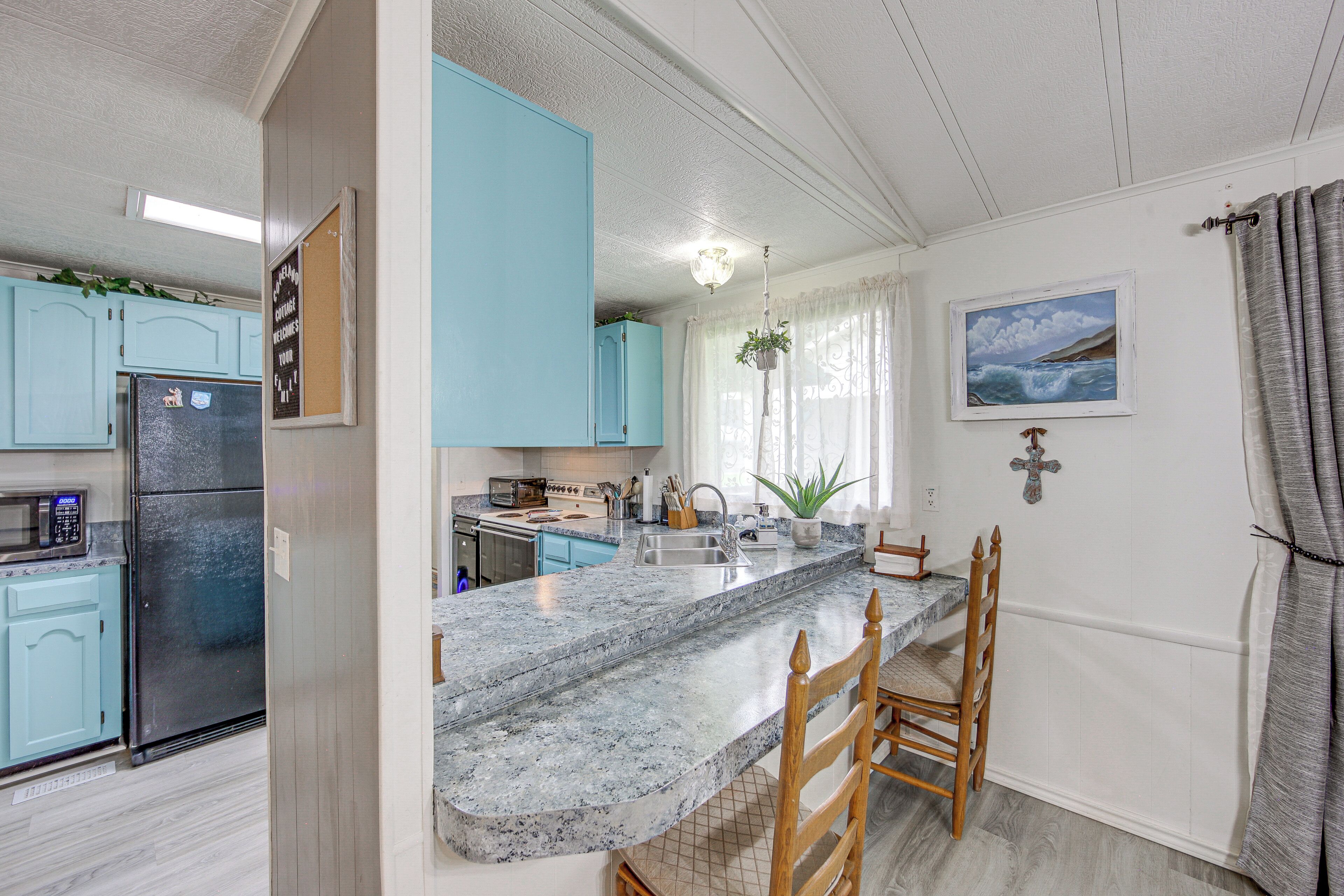 A kitchen with a granite countertop, a refrigerator, and light blue cabinets.
