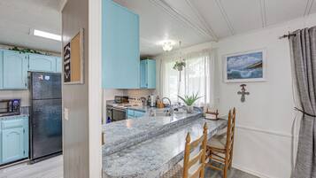 A kitchen with a granite countertop, a refrigerator, and light blue cabinets.
