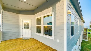 Un porche couvert avec un plancher en bois et une porte blanche.