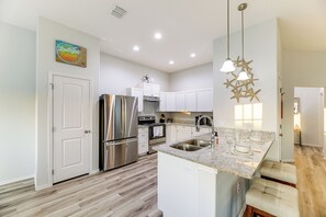 A modern kitchen with stainless steel appliances, a granite countertop, and pendant lighting. - Bright Rockport Vacation Rental w/ Community Pool! (Rockport)