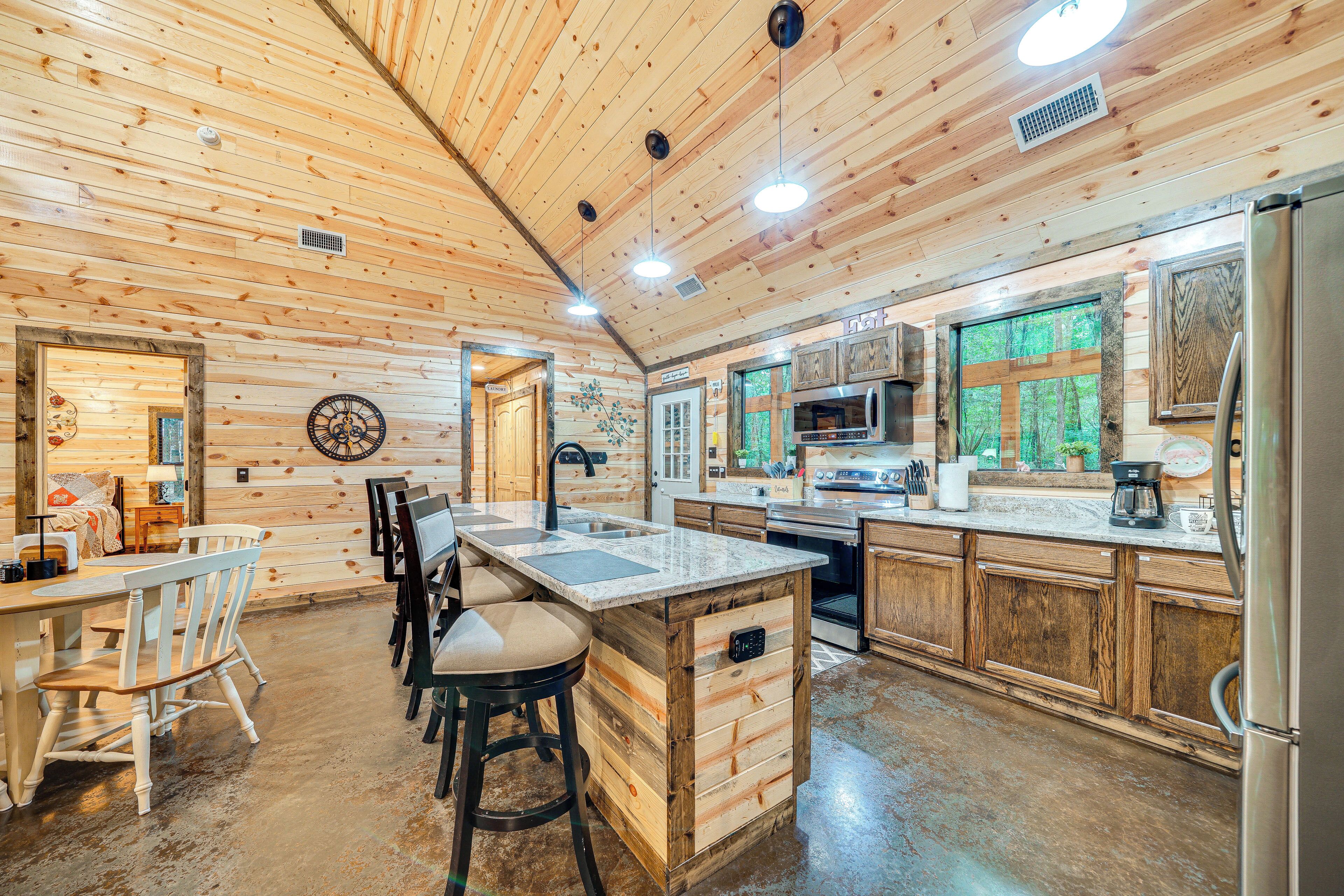 A wooden cabin interior with a kitchen, dining area, and bar stools.