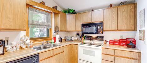 A kitchen with wooden cabinets, a dishwasher, a microwave, a stove, and a sink.
