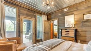 Une chambre confortable avec un grand lit, une commode en bois et une vue sur l’extérieur grâce à une porte vitrée.