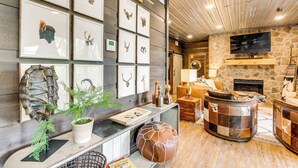 Un salon chaleureux avec une cheminée en pierre, un téléviseur fixé au mur et un pan de mur décoré de têtes d’animaux encadrées.