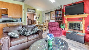 A living room with a leather sofa, a red armchair, a glass coffee table, and a fireplace.