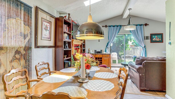 A dining area with a wooden table, chairs, and a hanging light fixture.