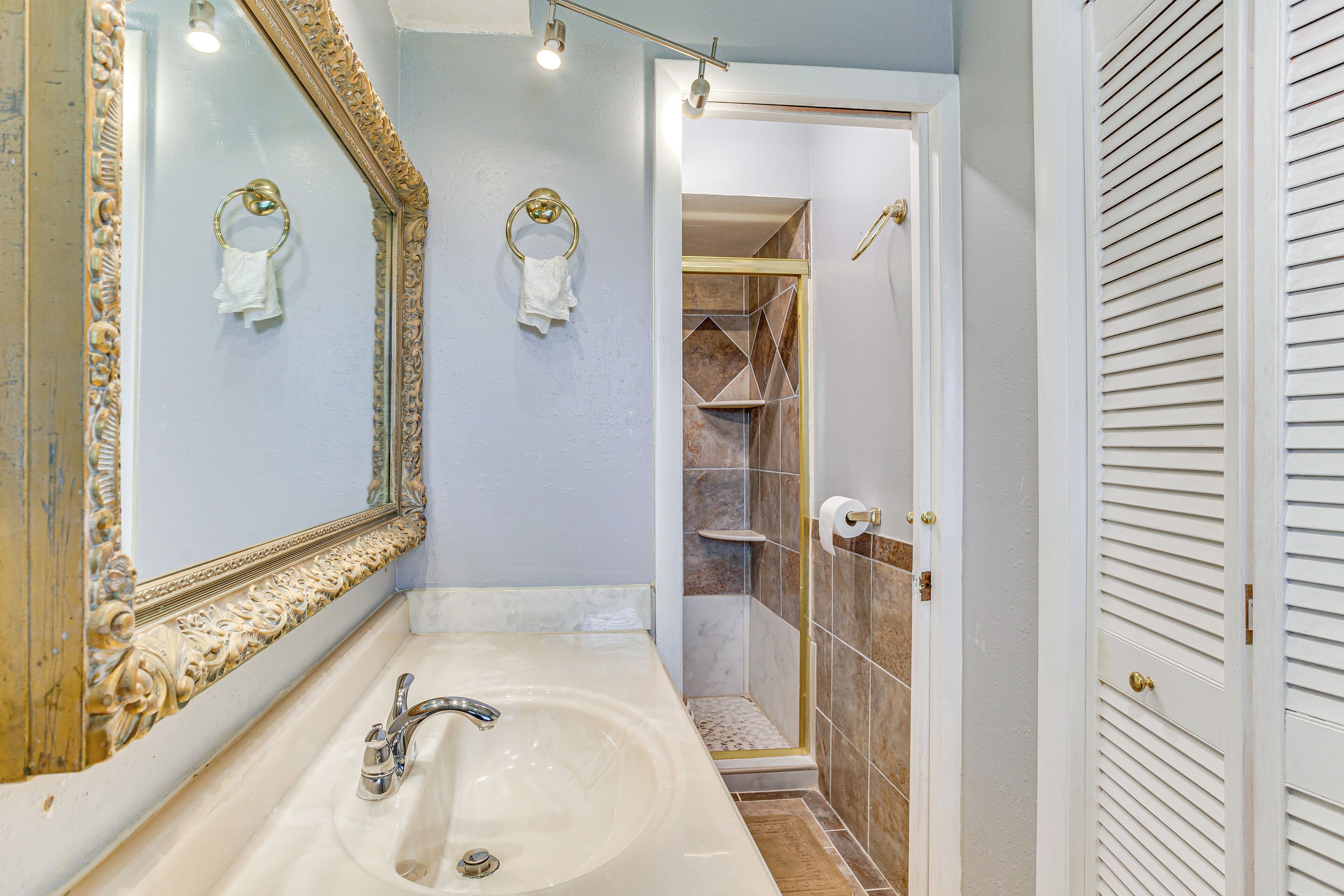 Un baño con un espejo grande, un lavabo y una zona de ducha.