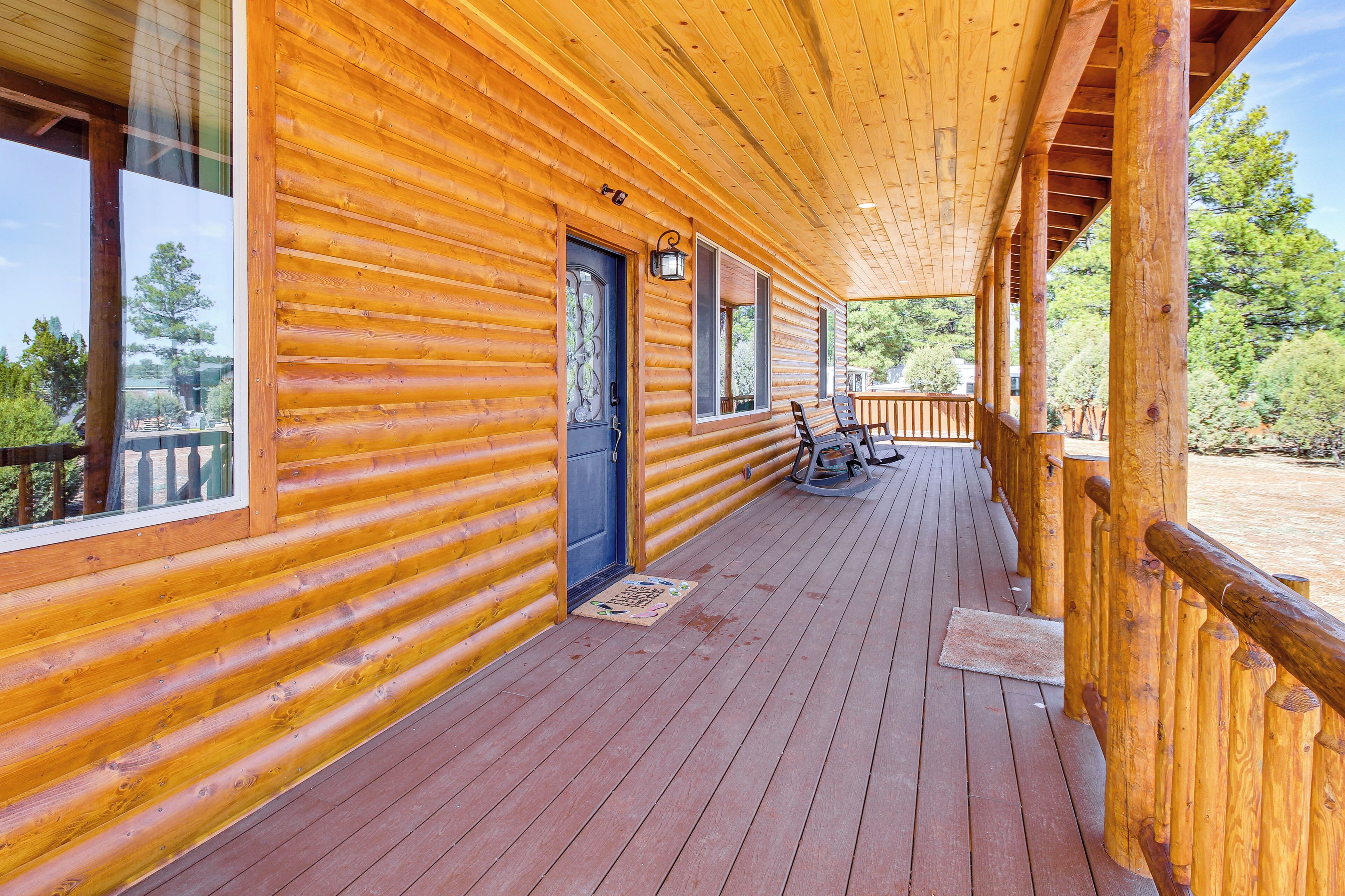 Une cabane en bois dotée d’un porche couvert, de grandes fenêtres et d’une porte ornée d’un panneau de verre décoratif.
