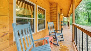 A wooden cabin with a porch featuring rocking chairs and a small table. - Broken Bow Cabin w/ Private Hot Tub: 14 Mi to Lake (Broken Bow)