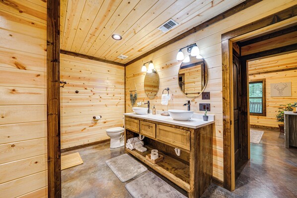 A wooden cabin bathroom with a wooden vanity, two sinks, a mirror, and a toilet. - Broken Bow Cabin w/ Private Hot Tub: 14 Mi to Lake (Broken Bow)