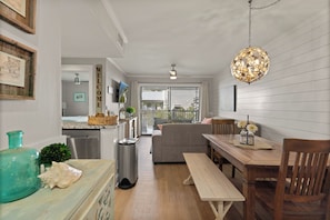 Cozy living space with a kitchen and dining area, featuring a large window, wooden table, and comfortable seating.