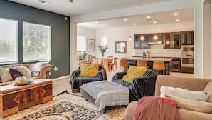 A spacious living room with a sofa, ottoman, and coffee table, a dining area with chairs, and a kitchen with cabinets and appliances. - Rio Bravo Country Club Home in Bakersfield w/ Pool (Bakersfield)