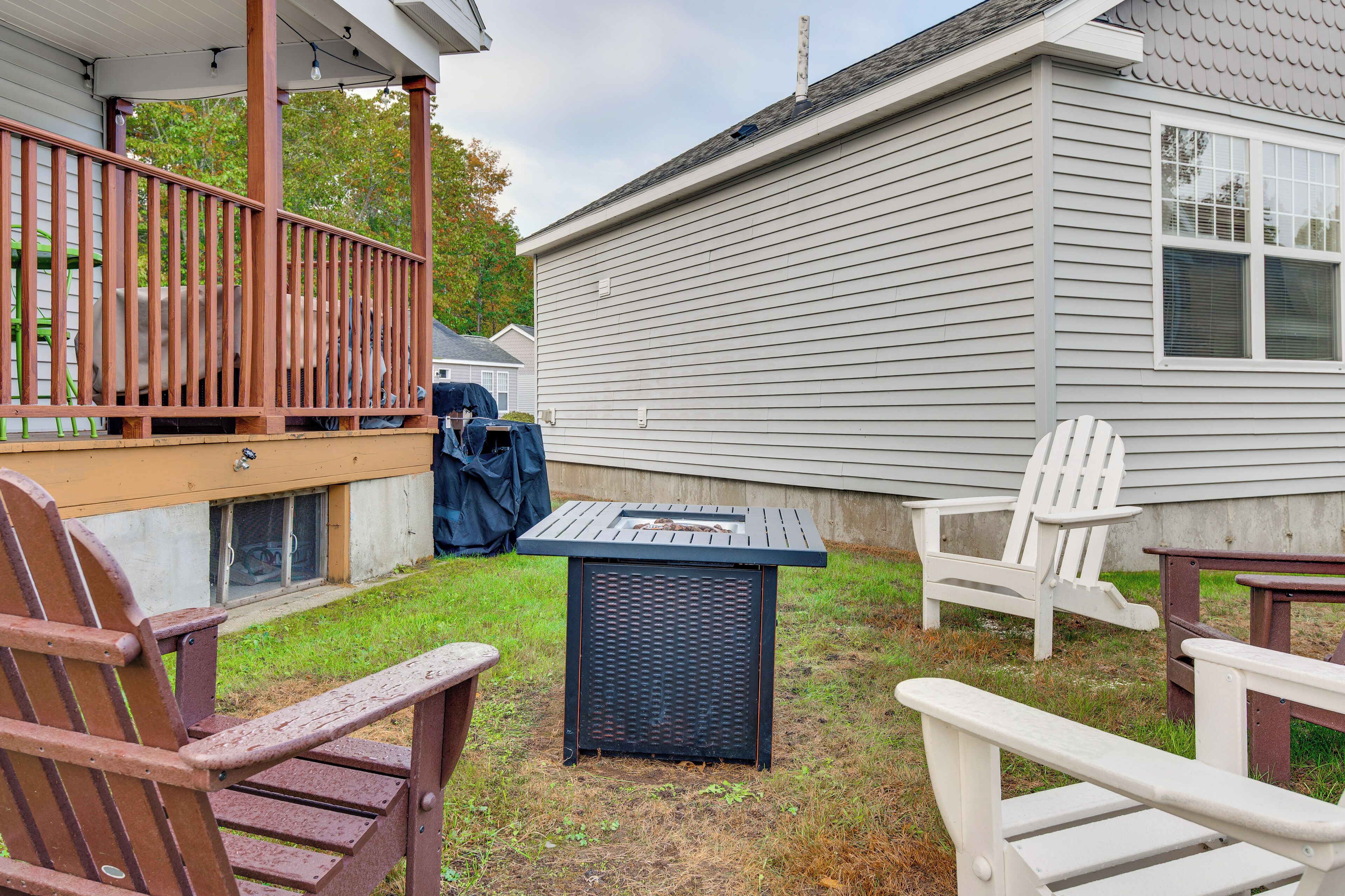 A backyard with a covered patio, outdoor seating, and a grill.