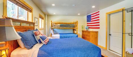 Un dormitorio con dos camas, cabeceros de madera, una lámpara, un aparador y una bandera estadounidense.