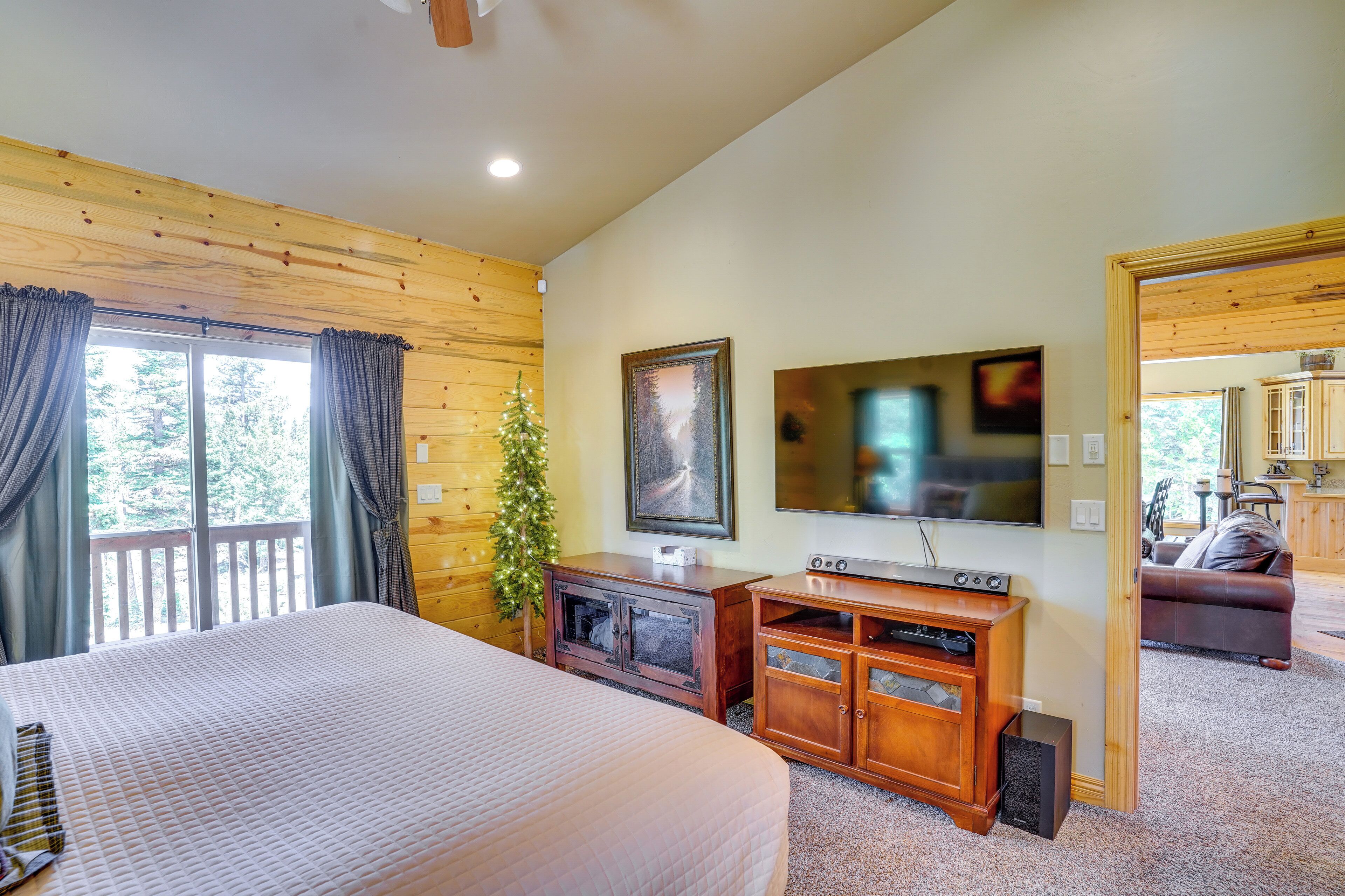 A bedroom with a large bed, wooden walls, a TV, and a small Christmas tree.