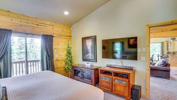 A bedroom with a large bed, wooden walls, a TV, and a small Christmas tree.