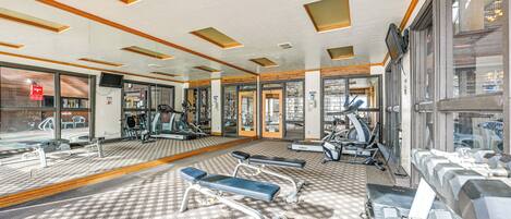A gym with exercise equipment, mirrors, and a patterned carpet.