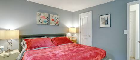 A bedroom with a large bed, two bedside tables, a nightstand, and a door.