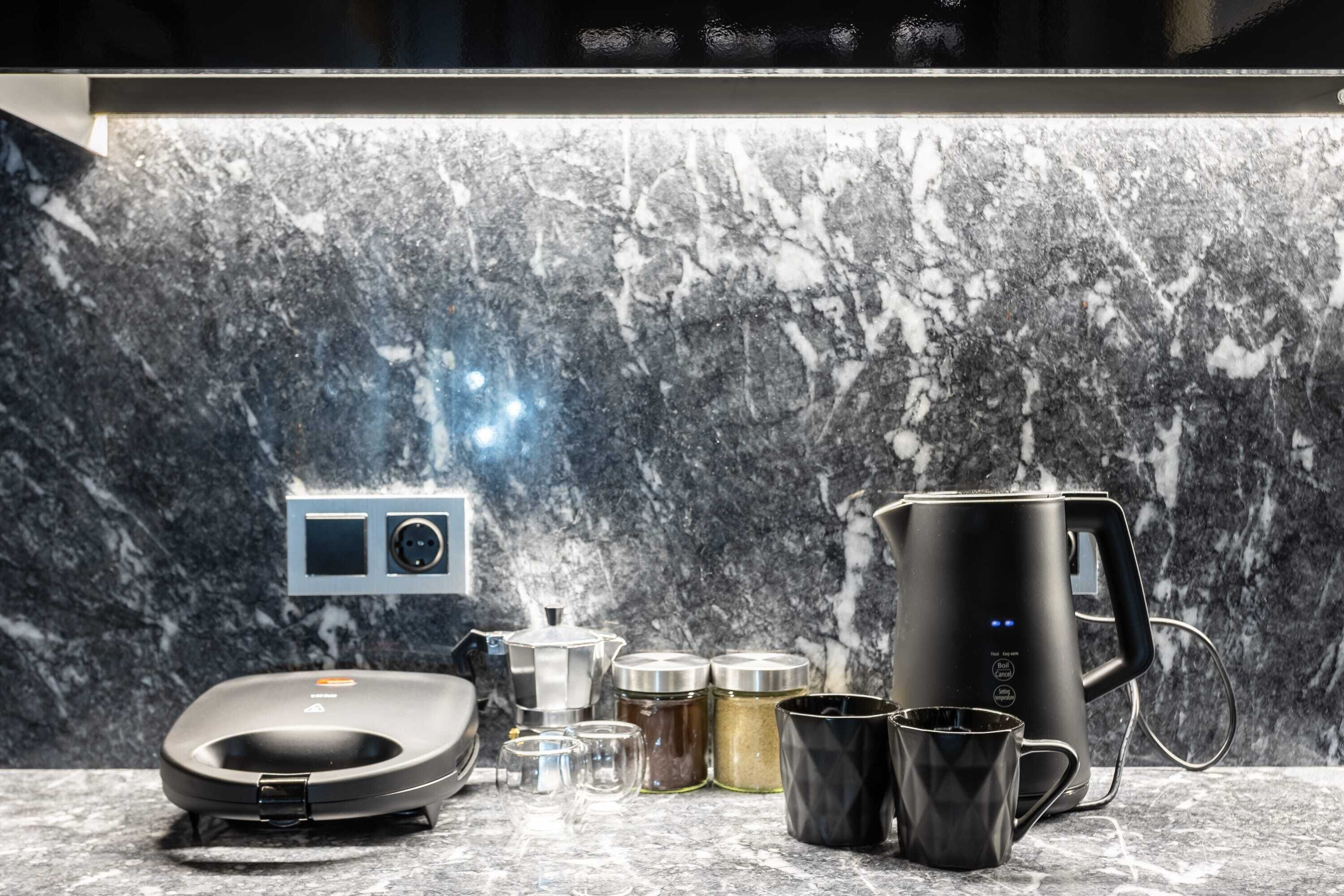 Une cuisine moderne dotée d’un pare-feu en marbre, d’une machine à café, d’une balance et de divers récipients.