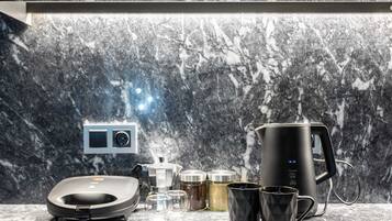 Une cuisine moderne dotée d’un pare-feu en marbre, d’une machine à café, d’une balance et de divers récipients.