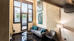 Ein modernes Wohnzimmer mit einer Couch, einem Sessel, einer Stehlampe und Kunstwerken an der Wand.
