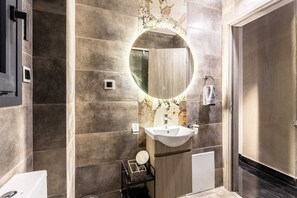 Ein modernes Badezimmer mit einem großen Spiegel, einem Waschbecken und einem Handtuchhalter.