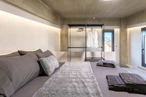 Une chambre à coucher moderne, avec un canapé, un lit, une armoire suspendue et une vue sur l’extérieur.