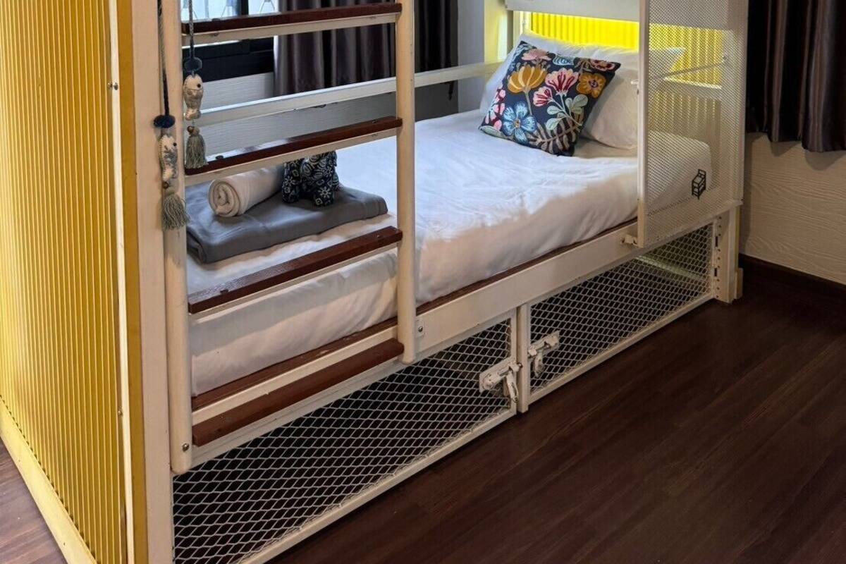 A bunk bed with a mesh side rail, a window with curtains, and a Samsung air conditioner on the wall.