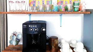 A kitchen area with a coffee maker, shelves with glass jars, and a variety of kitchenware. - Zanzicrown Hotel (Nungwi)