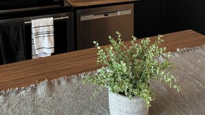 Eine moderne Küche mit einem Edelstahlherd, einer Spülmaschine und einer Holz Arbeitsplatte.